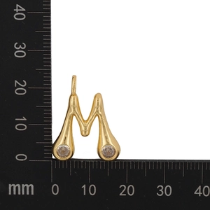 Detailed view of golden letter M pendant with clear zircons and liquid metal texture