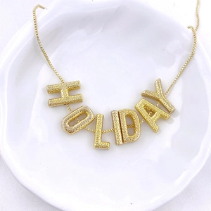 Polished gold plated HOLIDAY letter pendant necklace with textured finish for women