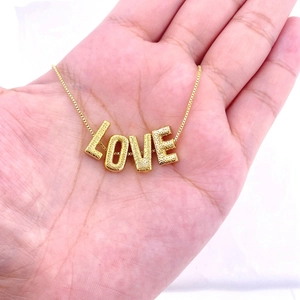 Detail showing the hammered texture of gold-plated LOVE letter pendants on a box chain