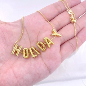Gold plated box chain necklace with textured HOLIDAY letter pendant and adjustable slider clasp