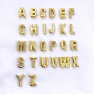 Flat lay of 26 gold plated copper alphabet beads with textured grainy surface finish
