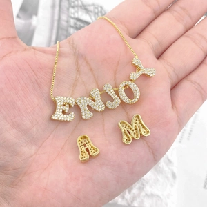 Detailansicht der vergoldeten Zirkon-Buchstabenanhänger und ENJOY-Halskette auf der Hand