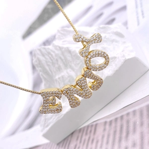 Detaillierte Nahaufnahme des goldenen ENJOY-Buchstabenanhängers mit Zirkonia-Besatz an Kette