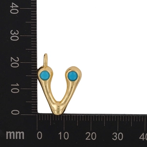 Macro detail showing 15mm gold V-shaped pendant with blue zircon stones on scale