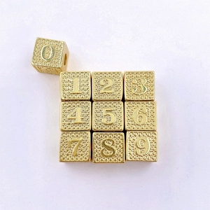 Detailopname van gouden vierkante cijferkralen 0-9 voor het maken van DIY-sieraden