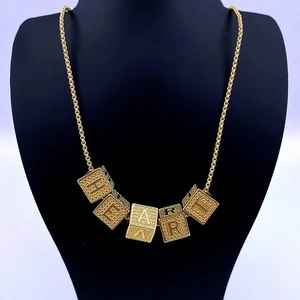 Hip hop style gold cube letter necklace featuring HEART pendants on a black neck model