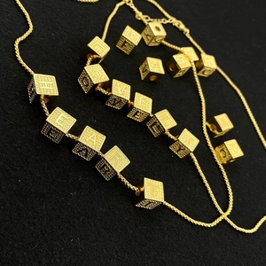 Golden hip hop cube letter necklace with textured cubic charms on black background