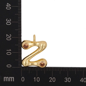 Macro detail of gold-plated Z letter pendant with orange zircon stones and size scale