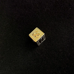 Macro-opname van een vergulde kubusvormige hanger met kristallen bezette letter S
