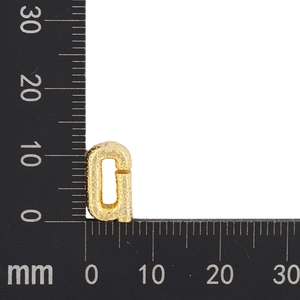 Macro shot of 12mm gold letter G pendant showing granular texture on measuring scale