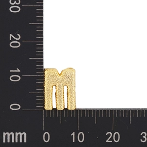 Macro detail of golden letter M pendant with textured finish showing 10mm height measurement