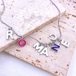 Detail view of ROMANCE colorful enamel letter pendants on a silver box chain necklace
