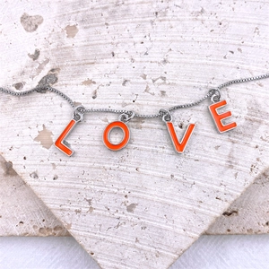 Macro shot of silver box chain necklace with vibrant orange enamel LOVE letter charms