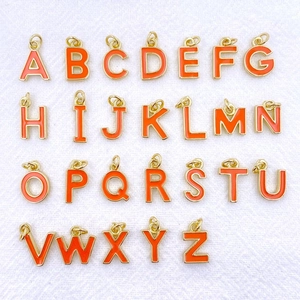 Vue détaillée des 26 breloques alphabétiques dorées et émail orange pour bijoux DIY