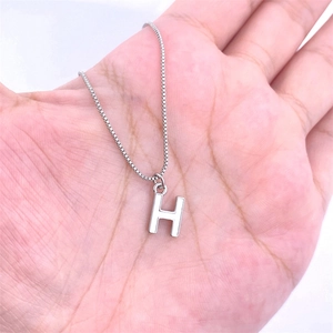 Polished silver initial H letter pendant with thin box chain held in hand