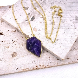 Primer plano de un collar vintage dorado con un gran colgante de amatista púrpura facetada
