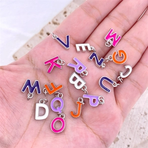 Macro shot of colorful enamel alphabet charms held in palm for DIY jewelry making