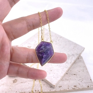 Primer plano de colgante de amatista violeta en forma de rombo con marco dorado y cadena