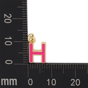 Pendentif lettre H en émail rose avec base dorée mesuré par règle pour dimensions