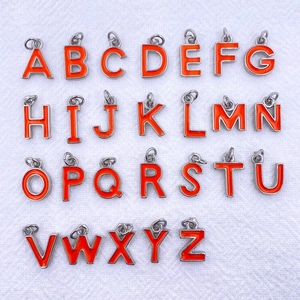 Detail of 26-piece silver metal alphabet charms with bright orange enamel finish for DIY crafts