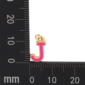Pendentif lettre J en émail rose avec base en métal doré mesuré sur une échelle millimétrée