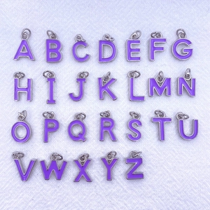 Detailed flat lay of 26 purple enamel letter charms for DIY necklace making
