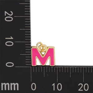 Vue détaillée du pendentif lettre M en émail rose doré avec règle de mesure millimétrée
