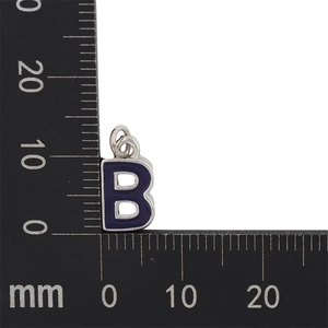 Macro shot showing 10mm silver letter B pendant with dark purple enamel on a measuring tool