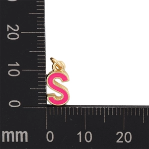 Vue macro du pendentif lettre S en émail rose avec base dorée et règle de mesure