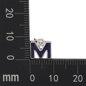 Macro shot of 11mm blue enamel letter M pendant on a scale ruler for size reference