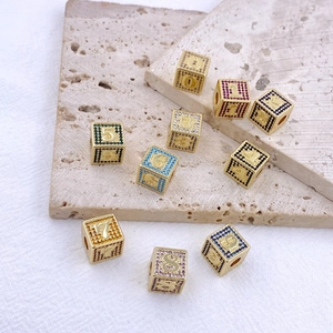 Dettaglio dei ciondoli a cubo dorati con numeri 0-9 in zirconi colorati scintillanti