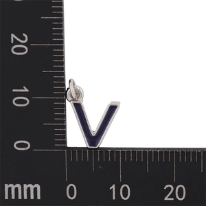 Macro shot of a silver letter V pendant with blue enamel and measurement ruler
