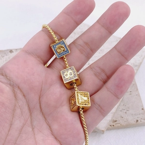Dettaglio di ciondoli a cubo dorati con numeri in zircone colorato su bracciale a catena