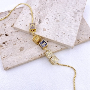 Collana a catena dorata con ciondoli a dado decorati con zirconi colorati e lettere