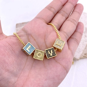 Dettaglio macro dei ciondoli con lettere LOVE e zirconi colorati su collana dorata