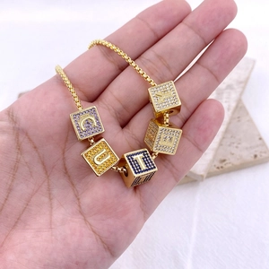 Collana a catena dorata con cinque ciondoli a dado con lettere e zirconi colorati