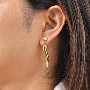 Vista detallada de pendiente cornicello chapado en oro de 18 quilates con perla en modelo