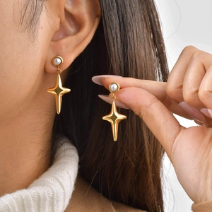 Detalle de pendientes de estrella bañados en oro de 18K con perlas en una modelo