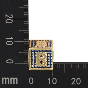 Macro del ciondolo a lettera B dorato con pietre di zircone blu e righello di misurazione