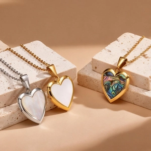 Detailed view of gold and silver heart lockets with mother of pearl inlay on stone base