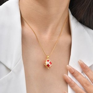Détail d'un collier avec pendentif œuf plaqué or et émail rouge et blanc vintage