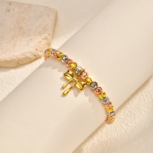 Three-tone beaded bracelet with golden bow charm on minimalist stone display