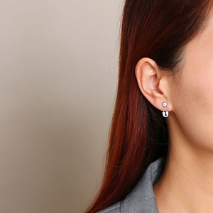 Silver safety pin earrings with zircon stones worn by a female model in profile