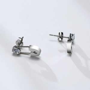 Macro view of silver safety pin earrings with sparkling round zircon and butterfly back