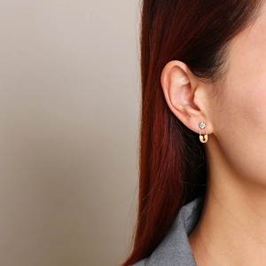 Close-up of a gold safety pin earring with zircon stone worn on model ear