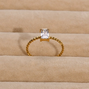Primer plano de un anillo trenzado dorado con una circonita cúbica rectangular elegante
