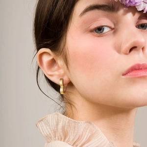 Elegant gold heart-shaped hoop earrings for women worn by a model in a fashion setting