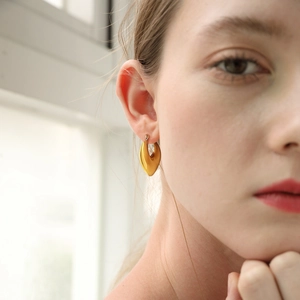 Detail van een minimalistische gouden U-vormige hartoorbel gedragen door een model