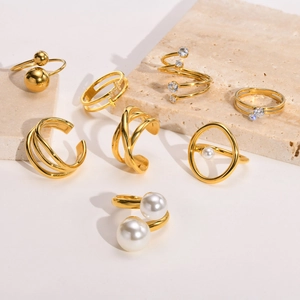Conjunto detallado de anillos y ear cuffs de acero dorado con perlas y circonitas