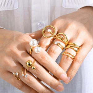 Conjunto de anillos dorados de acero inoxidable con perlas y cristales en la mano de una modelo